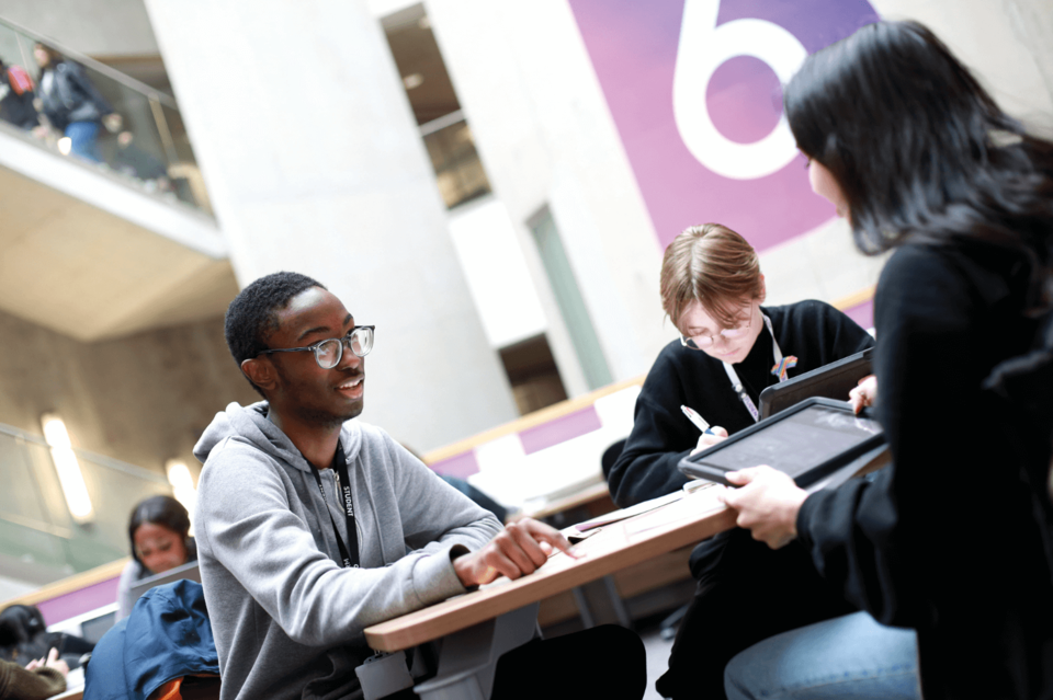 Image of three students studying at a table using Ipads