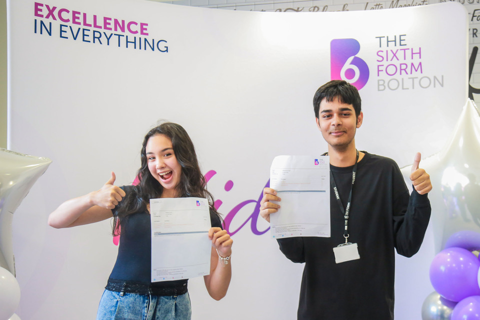 Two students holding up their results
